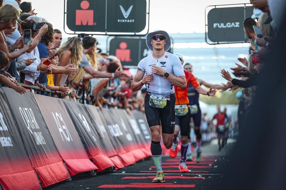 Arrivée d'un triathlon longue distance, le public tend la main vers le coureur